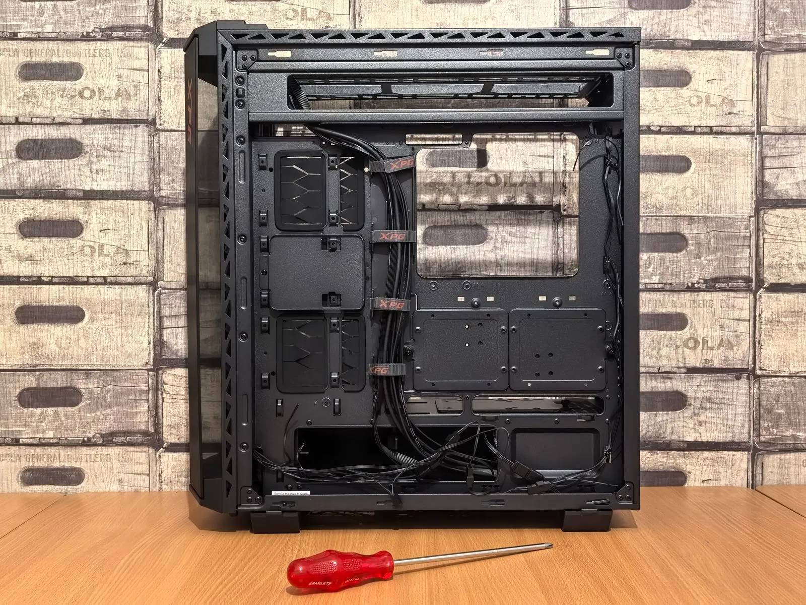 Open computer case ready for installation, with screwdriver placed nearby on desk.